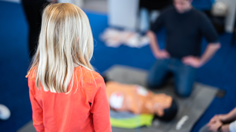 Child watching an AED and CPR training session at school